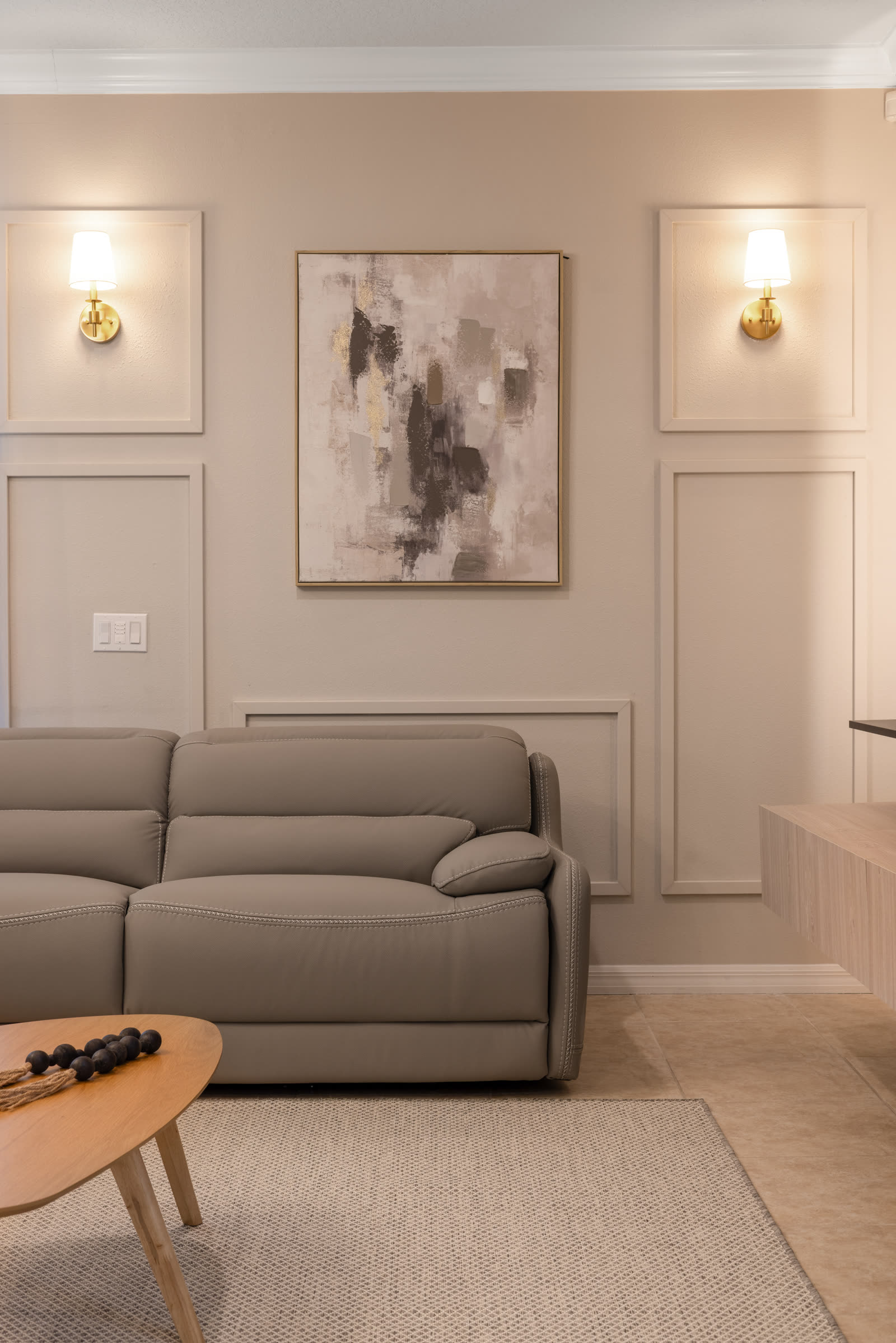 Neutral living room with wall paneling and sconce lighting in a Central Florida home