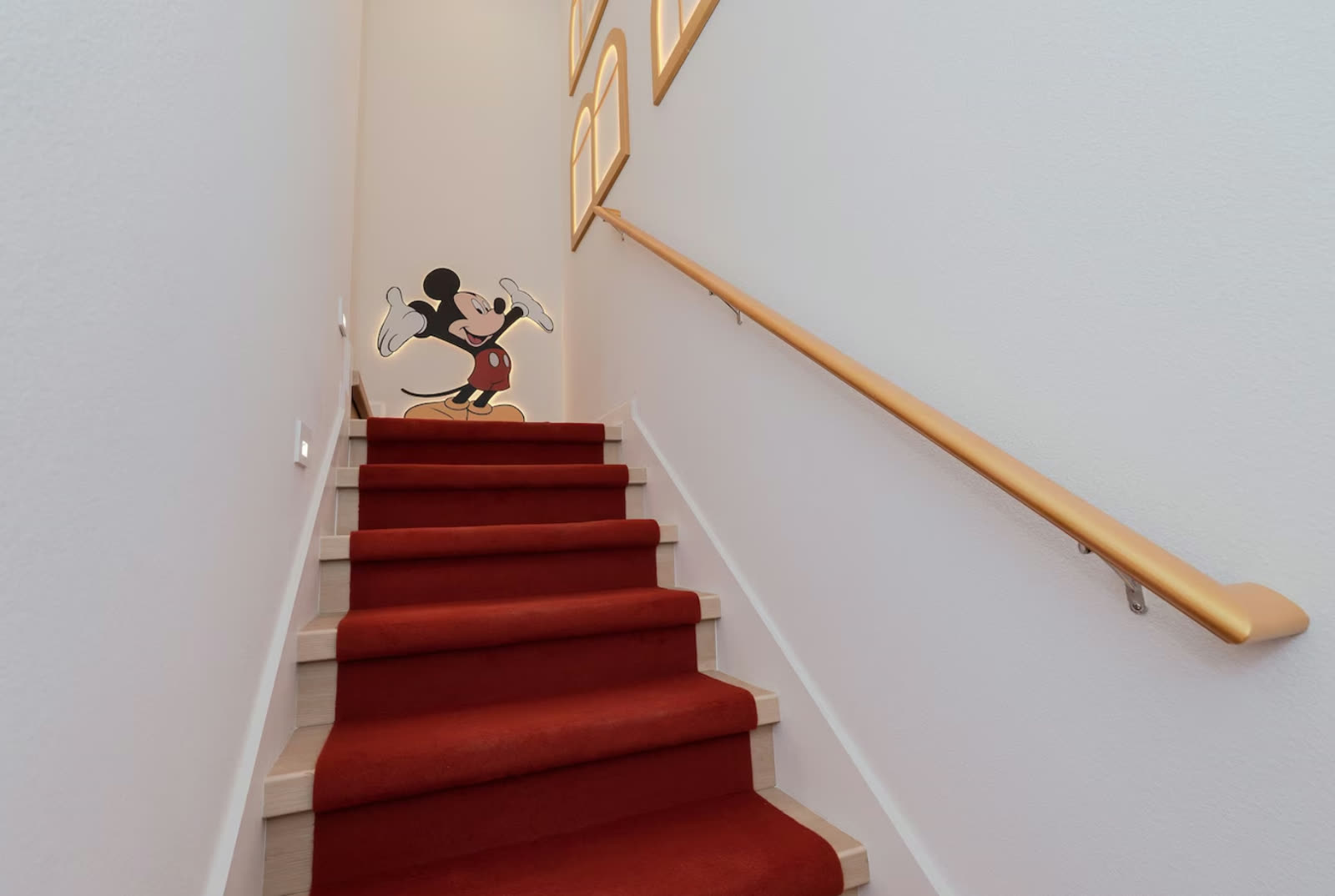 Custom Mickey Mouse staircase detail with red runner in an Orlando vacation home